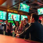 Experience the excitement of Sports Betting with enthusiastic bettors celebrating in a lively sportsbook setting.